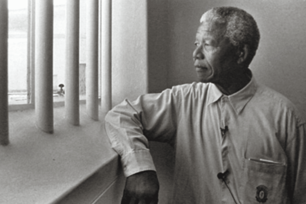 Nelson Mandela looking out the window of his prison cell on Robben Island. Image Credit: Jurgen Schadeberg