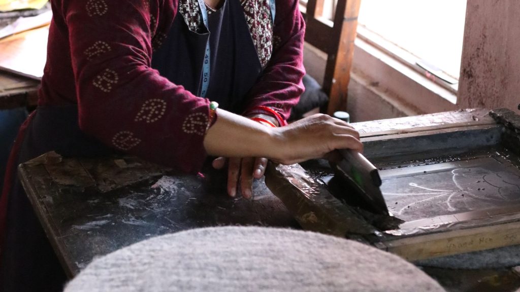 Artisan working by hand on textile craft in a workshop, demonstrating traditional craftsmanship and ethical production practices