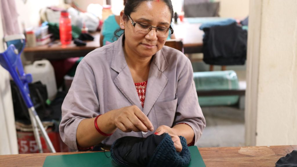 Artisan sewing handmade fabric products in a small workshop using traditional textile techniques