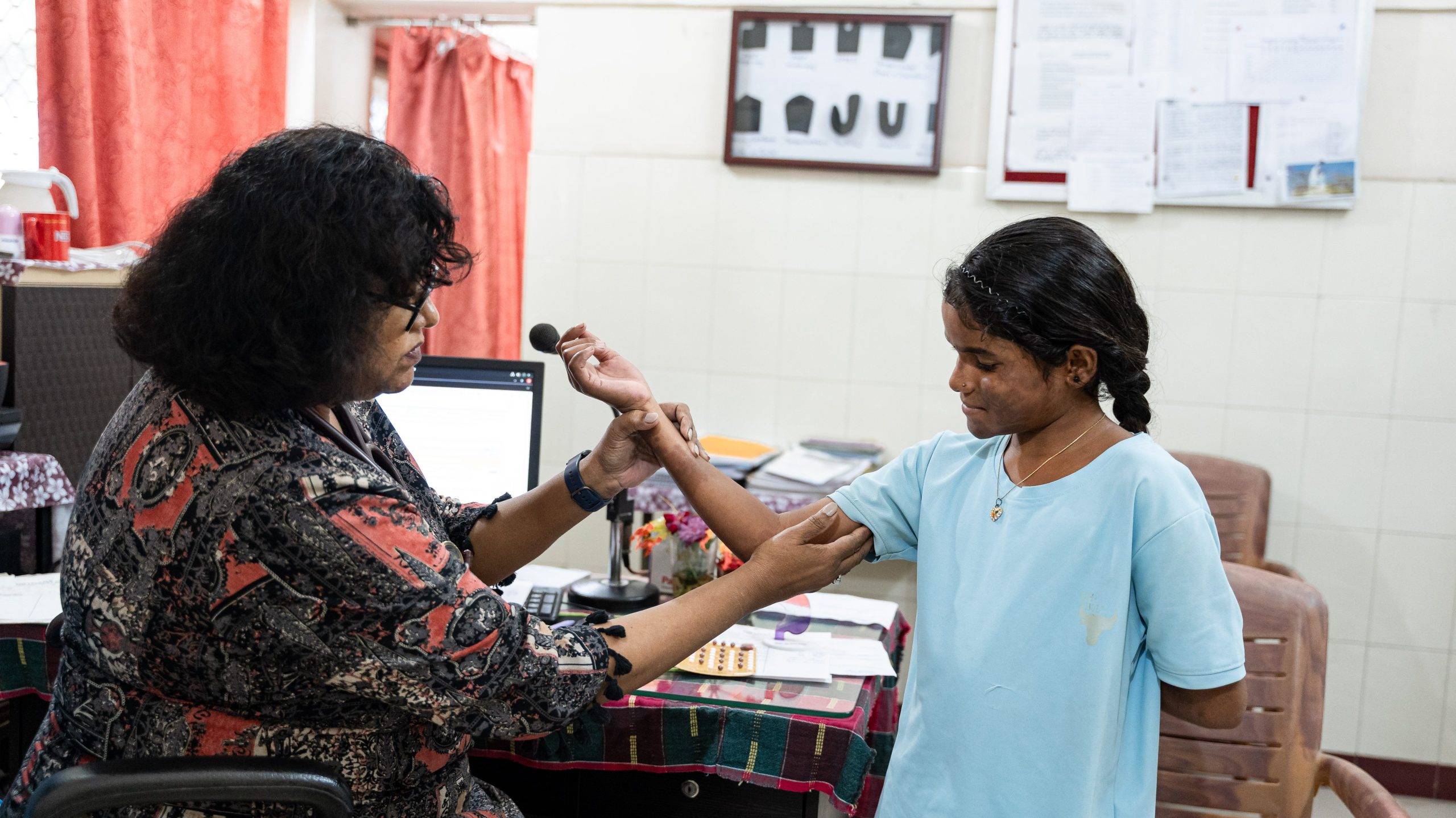 A healthcare worker smiles while caring for a child in a hospital ward.