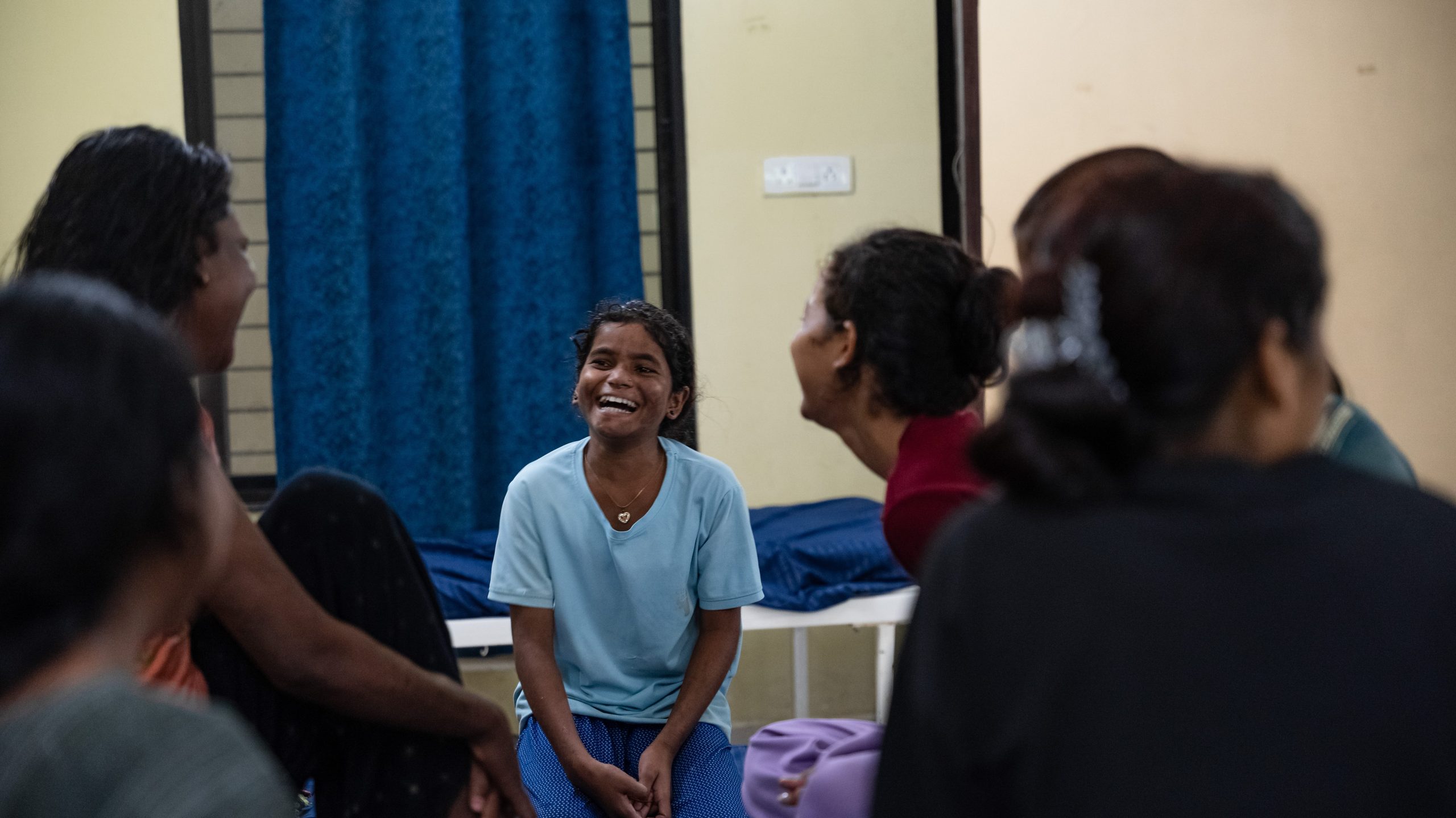 Children sit together and play games in a hospital setting.