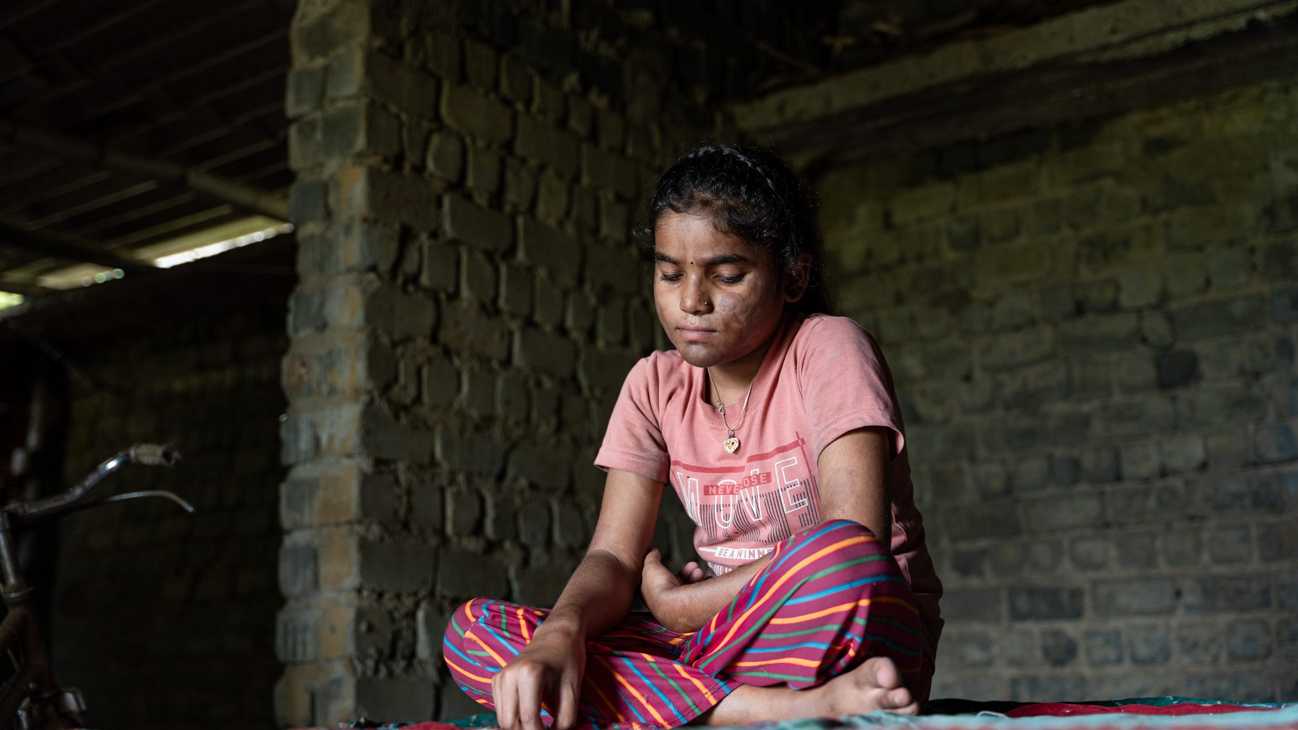A young girl sitting at home in a rural area.
