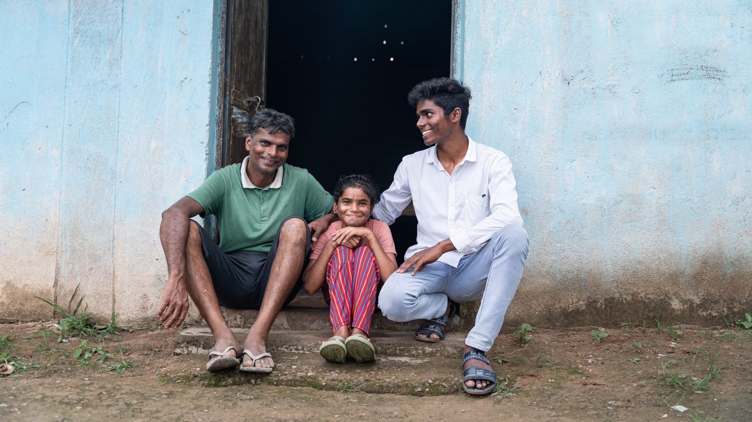 A young girl smiles while sitting with her family.