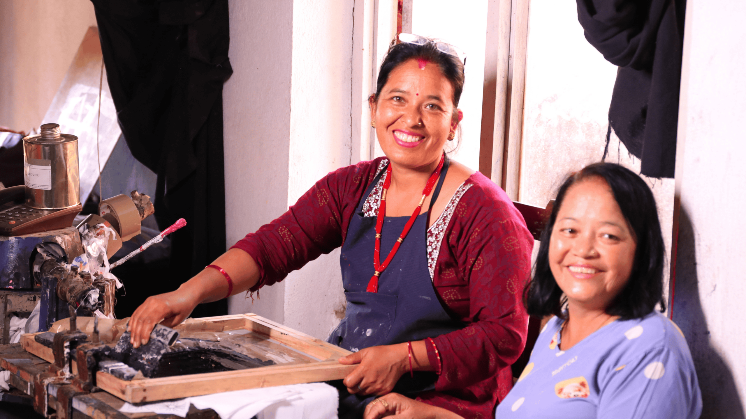 Smiling artisan working in a fair trade workshop surrounded by handmade products.