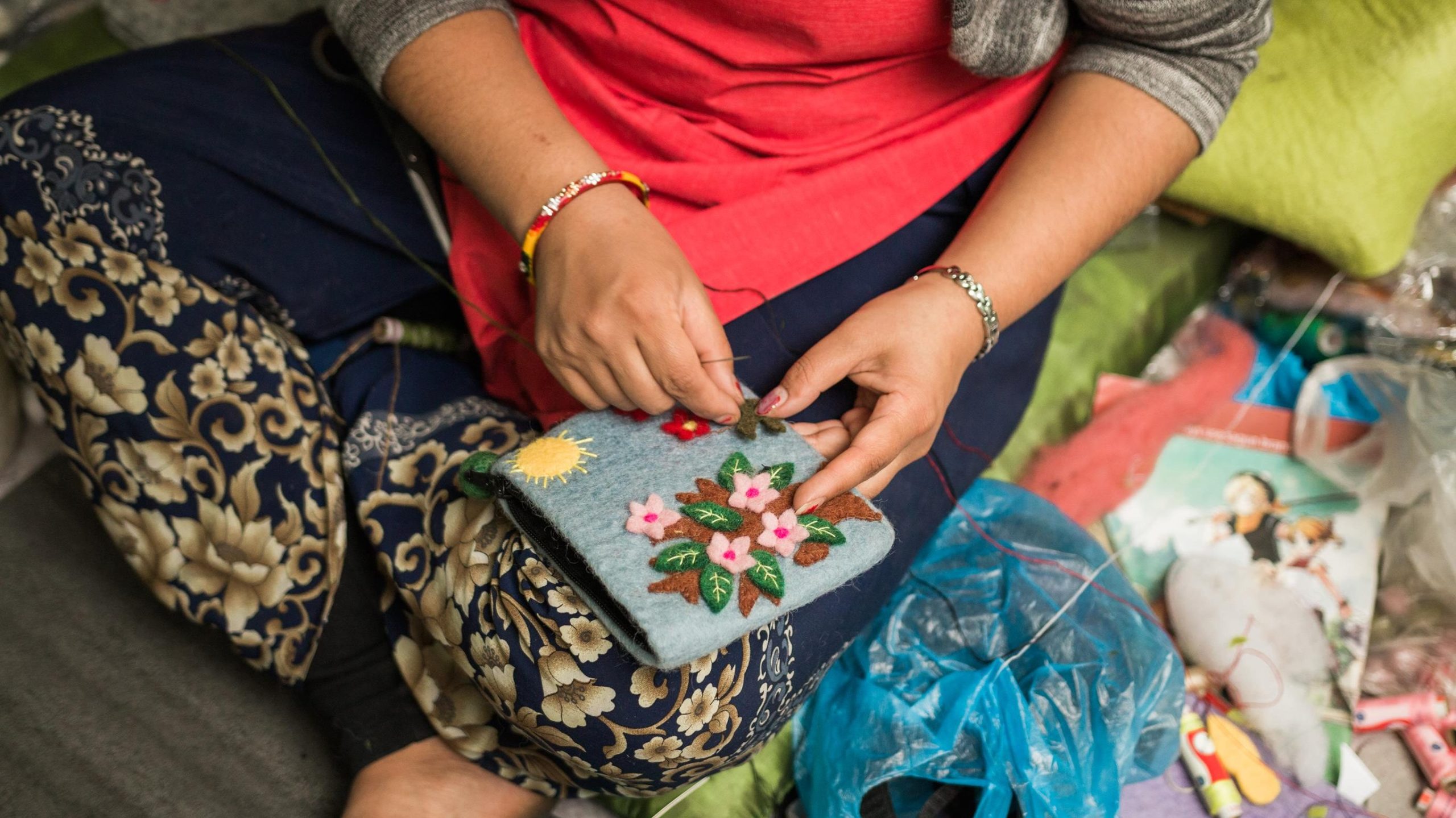 Close-up of artisan hands weaving fabric on a loom showing traditional textile craftsmanship.