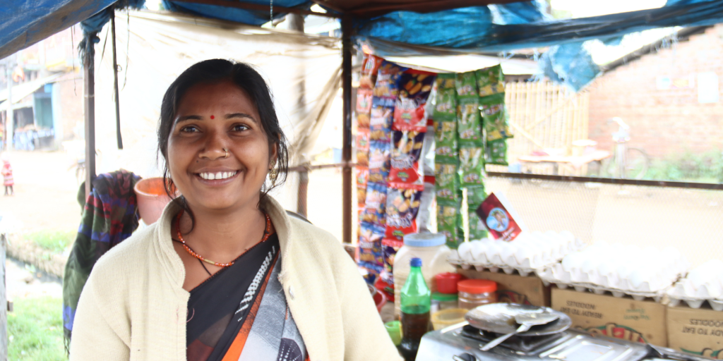 Urmila standing beside her mobile snack cart in rural Nepal.
