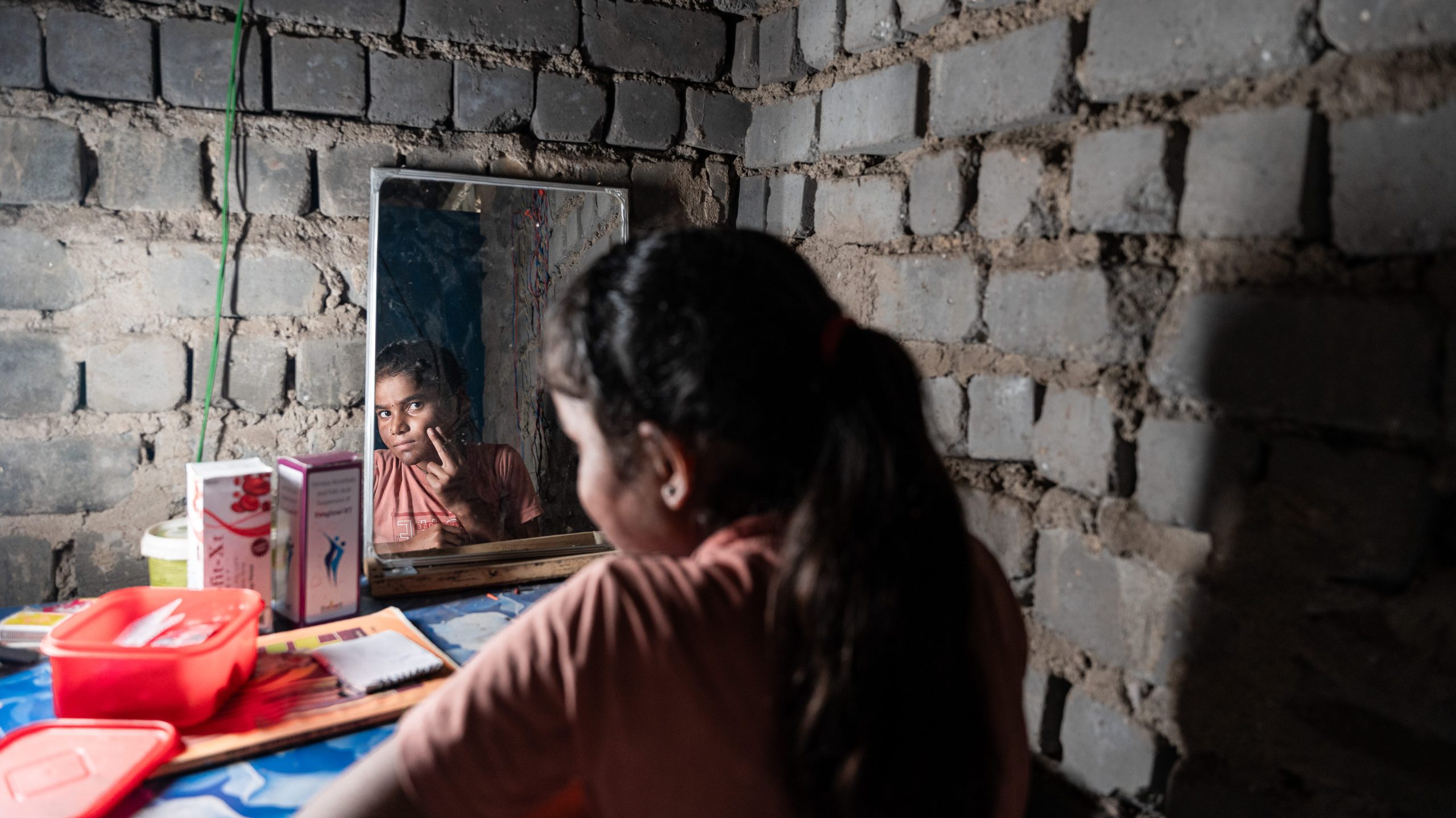 Nisha in her home looking in the mirror.
