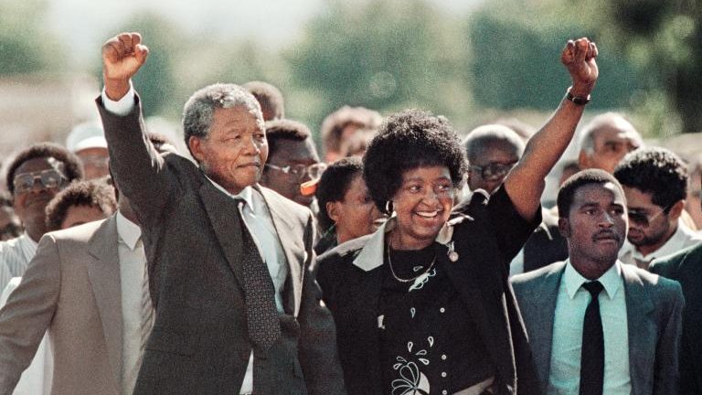 Nelson Mandela and Winnie Mandela raise their fists in a gesture of unity and hope following his release from prison.