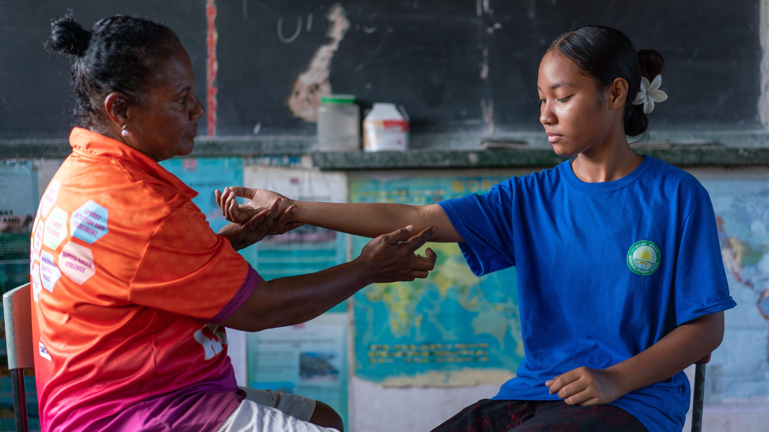 A woman giving a student a medical assessment for leprosy